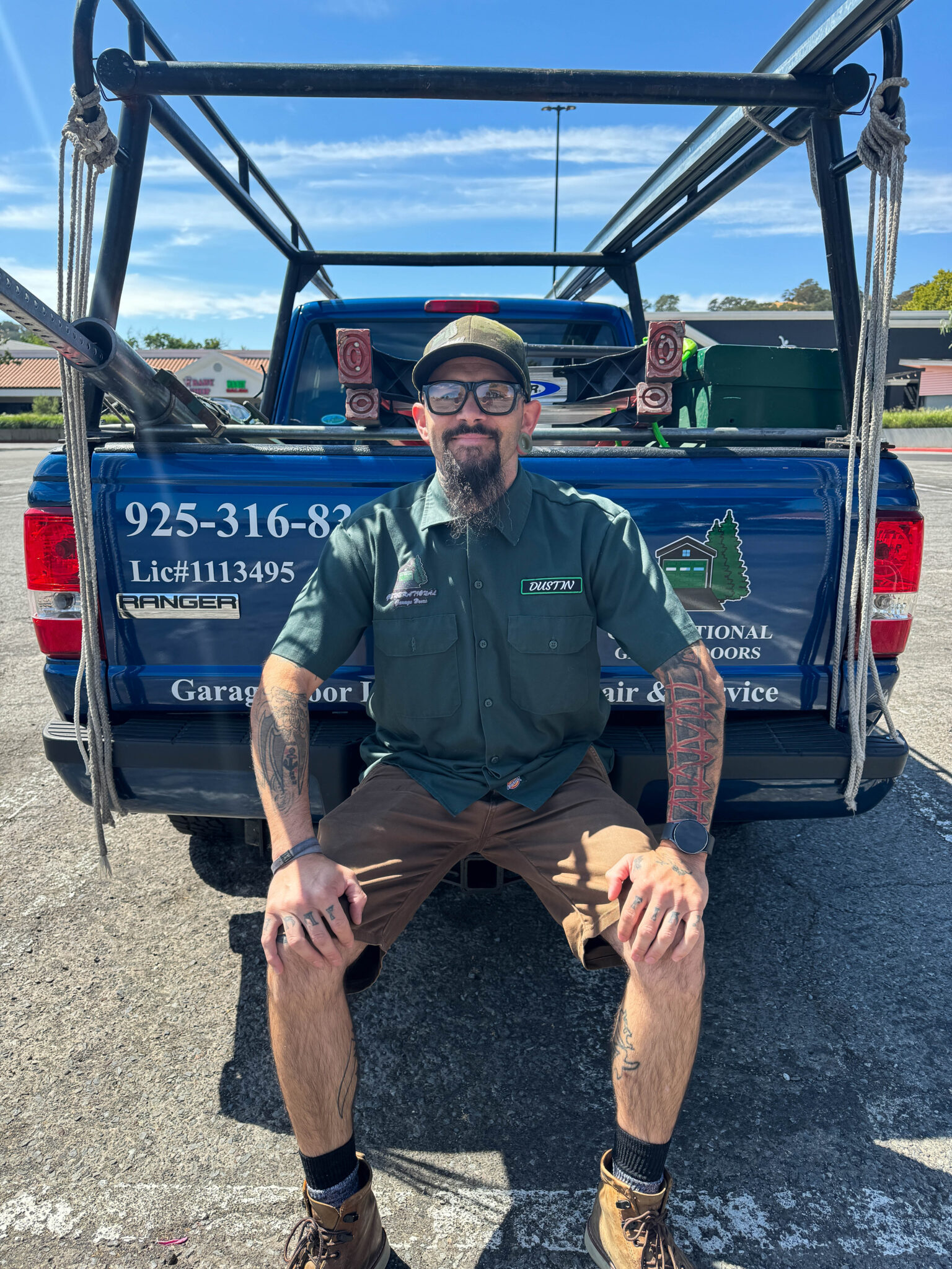 Dustin Cantu owner of Generational Garage Doors sitting on the back of his marked service truck — owner-operated garage door company Martinez CA